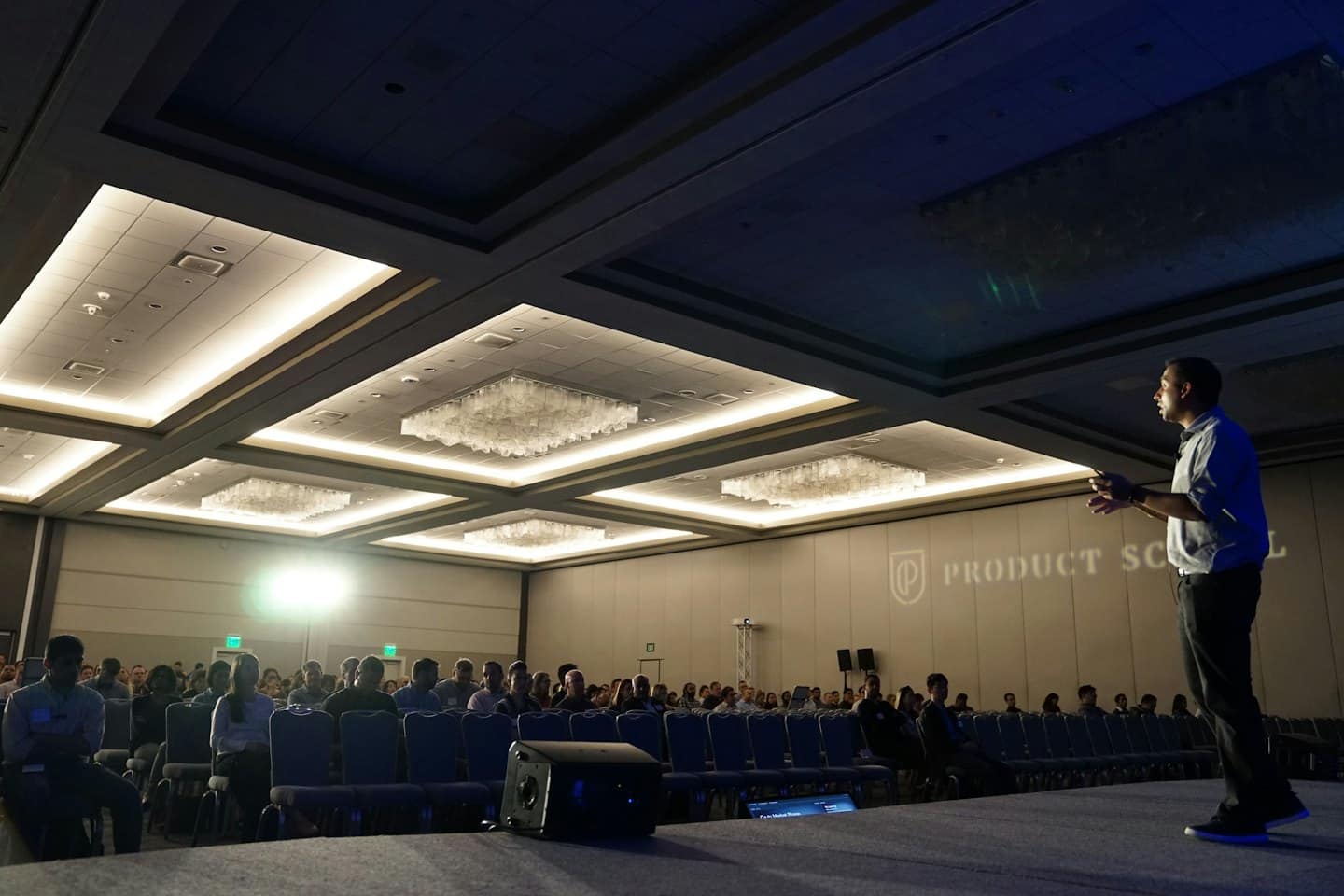 Man presenting on stage to a large audience.