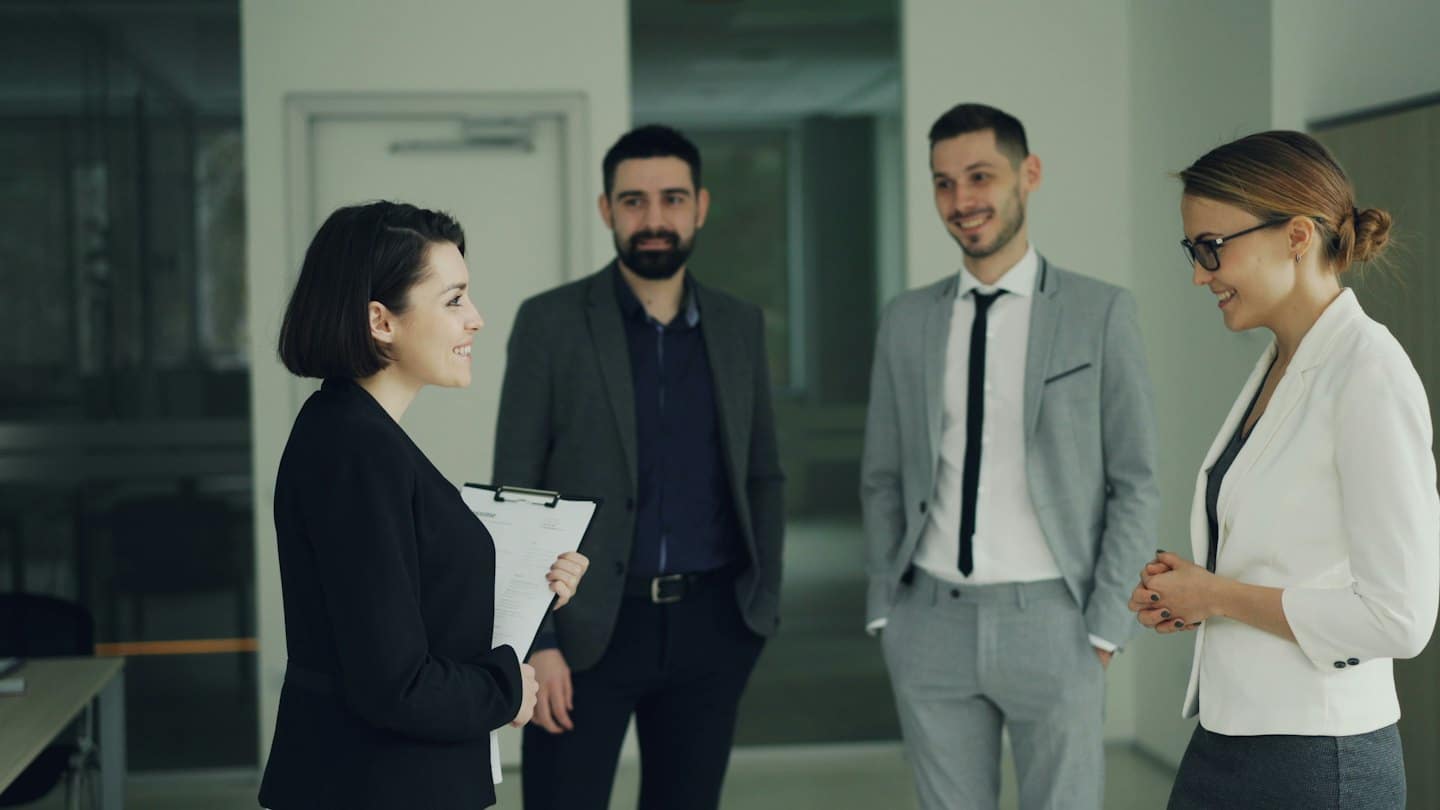Business professionals discussing ideas in a modern office hallway.